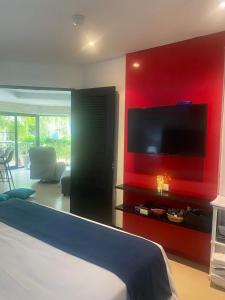 1 dormitorio con pared roja y TV de pantalla plana en Dewa One bedroom suite en Nai Yang Beach