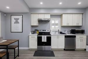 uma cozinha com armários brancos e um fogão a preto e branco em Spacious 4 BR House in Park Drive em Vancouver