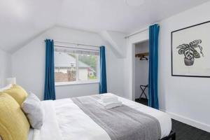 a bedroom with a bed with blue curtains and a window at The Spacious Haven at West 27th in Vancouver