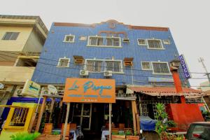 un bâtiment bleu avec un panneau devant lui dans l'établissement Hotel Le Prince, à Cotonou