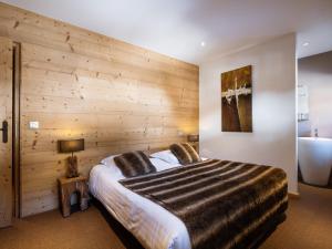 a bedroom with a large bed with a wooden wall at Appartement La Clusaz, 4 pièces, 6 personnes - FR-1-304-286 in La Clusaz