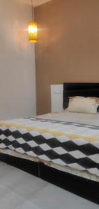 ein Bett mit einer schwarz-weißen karierten Decke in der Unterkunft PALM HOME in Kharar