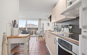 cocina con armarios blancos, mesa y sillas en Beautiful Apartment In Fan With Kitchen en Fanø