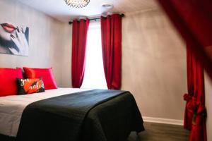 a bedroom with a bed with red curtains and a window at Date Night - Ooo La La in Knoxville