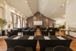 a conference room with tables and chairs and a projection screen at Eight Hotel Ari in Bangkok