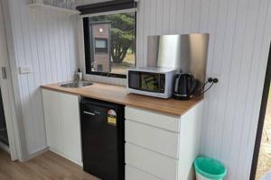 eine Küche mit einer Theke mit einer Mikrowelle und einer Spüle in der Unterkunft Tiny House 18 at Grampians Edge in Dadswells Bridge