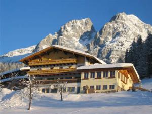 a building in the snow in front of a mountain at Ferienhotel Samerhof in Pfarrwerfen