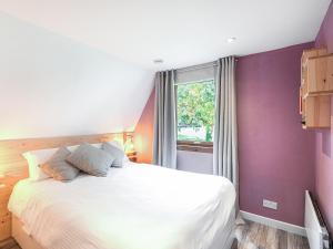 a bedroom with a white bed with purple walls and a window at Lodge 6, Invergarry Lodges in Fort Augustus
