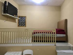 Cette petite chambre comprend un lit bébé et une télévision. dans l'établissement Grand Hagawa Syariah near Alun Alun Lamongan RedPartner, à Lamongan