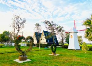 a park with a windmill and plants in the grass at WHITE Houseรีสอร์ท in Ban Bung Thap Tae (1)