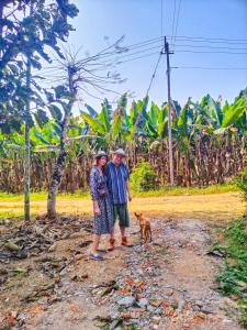 dos personas y un perro parado en un camino de tierra en CentreHome Villa Wayanad, en Meenangadi
