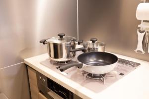 a pan and two pots on a stove in a kitchen at shirokane apartment Vx in Tokyo