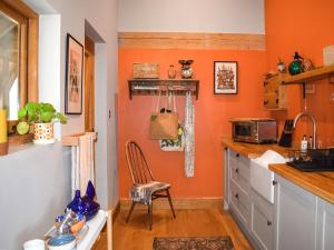 een keuken met oranje muren en een stoel bij The Stables in Heathfield