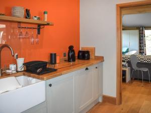 een keuken met een wastafel en een oranje muur bij The Stables in Heathfield