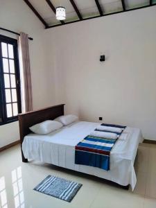 een slaapkamer met een bed met witte lakens en kussens bij Colombo Villa Near Bolgoda Lake 5 Bed 2.5 Bath in Piliyandala