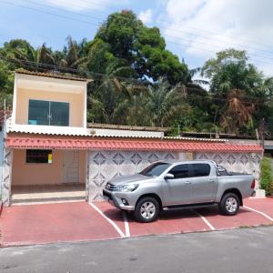 un camion argenté garé dans un parking en face d'une maison dans l'établissement DUPLEX ALTO PADRÃO NO COND. OURO NEGRO - COROADO, à Manaus