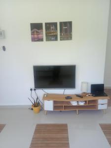 sala de estar con mesa y TV de pantalla plana en chalet aircond RM50 homestay aircond RM100 Kakmah pantai timur guest house, en Kuala Terengganu