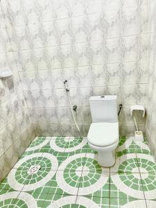 a bathroom with a toilet and a green and white tile floor at Mystic Manor Stonetown B&B in Stone Town