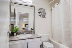 a white bathroom with a toilet and a sink at CozySuites - 2BR with Direct Skybridge Access #10 in Indianapolis