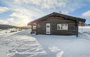 Una cabaña de madera en la nieve con el sol detrás. en 6 Bedroom Cozy Home In Kvam en Kvam