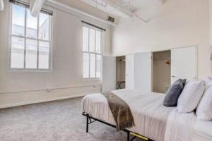a white bedroom with a large bed and two windows at CozySuites 2BR - 2BA with Skybridge Access #1 in Indianapolis