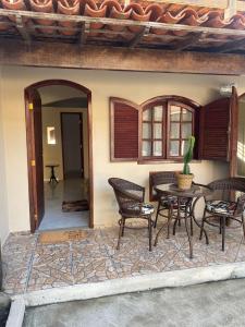 patio ze stołem i krzesłami obok budynku w obiekcie Villa Palmeiras Suítes w mieście Cabo Frio
