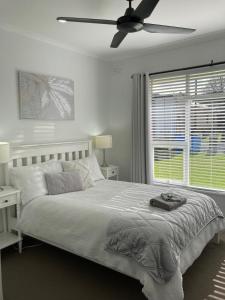 a white bedroom with a bed and a ceiling fan at Rosa's Apartment in Mount Gambier