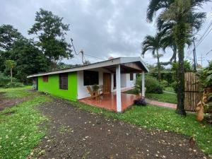 una pequeña casa verde y blanca con porche en Hijos del Bosque, en Bijagua