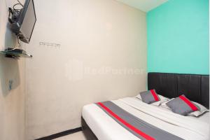 ein Schlafzimmer mit einem Bett und einem TV an der Wand in der Unterkunft J&B Rooms Utan Kayu Jakarta Mitra RedDoorz in Jakarta