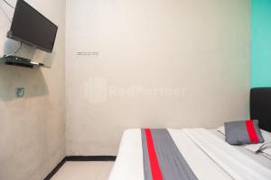 a room with a bed with a television on the wall at J&B Rooms Utan Kayu Jakarta Mitra RedDoorz in Jakarta