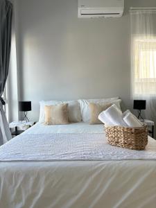 a white bed with pillows and a basket on it at House near the beach in Nai Yang Beach