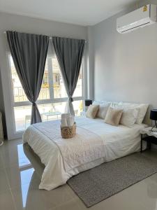 een witte slaapkamer met een groot bed met een mand erop bij House near the beach in Nai Yang Beach