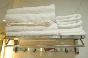 einen Stapel weißer Handtücher auf einem Kleiderständer im Bad in der Unterkunft Gia Kiên Hotel in Quy Nhon