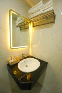 ein Badezimmer mit einem Waschbecken, einem Spiegel und Handtüchern in der Unterkunft Gia Kiên Hotel in Quy Nhon