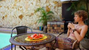 uma mulher sentada numa mesa com um prato de melancia em Casa Arq em Cali