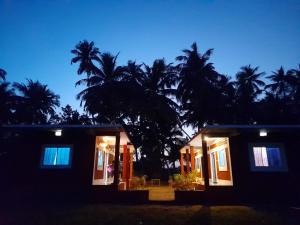 Sun Kissed Beach Stay في جوكارنا: منزل في الليل مع أشجار النخيل في الخلفية