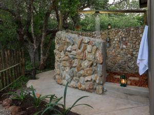 a stone wall with a bath tub in a yard at Grace of Africa, Kruger Couples Nature Lodge in Marloth Park