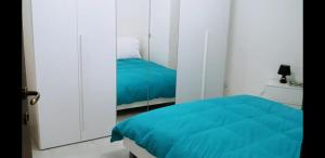 1 dormitorio con cama azul y espejo en Beautiful Newer Scalea Beach Apartment en Scalea