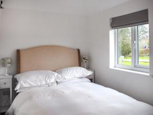 uma cama branca com almofadas brancas e uma janela em Cripps Cottage Annex em Hassocks