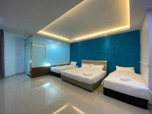 a bedroom with two beds and a blue wall at Codidik Hotel in Kuantan
