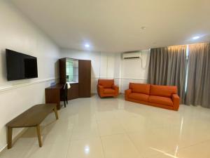 sala de estar con muebles de color naranja y TV de pantalla plana. en Codidik Hotel, en Kuantan