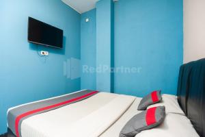 um quarto com uma cama com uma parede azul em J&B Rooms Pramuka Jakarta Mitra RedDoorz em Jakarta
