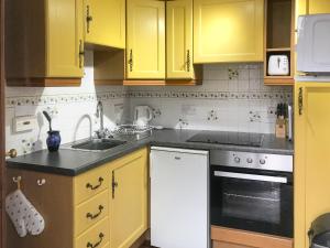 a kitchen with yellow cabinets and a sink at Honeysuckle Cottage - Uk4177 in Mayfield