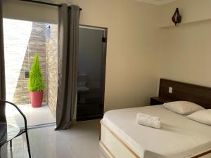 a bedroom with a bed and a window with a plant at Hotel Novo Apúlia in Sao Paulo