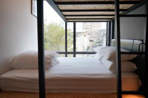 1 cama con almohadas blancas en una habitación con ventana en 瀚寓夏天 Hanns Summer, en Taipéi