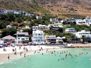 a group of people on a beach in the water at 24 Gordonia, Sleeps 7, Beach Front condo - Load-shedding friendly with Solar Power and battery backup in Gordonʼs Bay