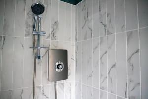 W łazience z białymi ścianami wyłożonymi kafelkami znajduje się prysznic. w obiekcie Beach Apartments - 1st Floor Cleveleys w mieście Cleveleys