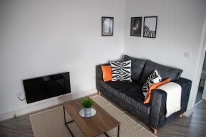 ein Wohnzimmer mit einem schwarzen Sofa und einem Tisch in der Unterkunft Beach Apartments - 1st Floor Cleveleys in Cleveleys