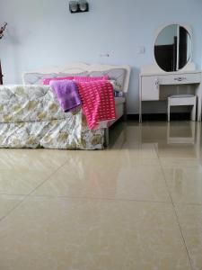 a bedroom with a bed and a mirror and a tiled floor at Mariana Shared Home in Dar es Salaam