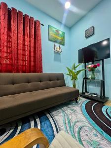 uma sala de estar com um sofá e uma televisão de ecrã plano em HH Homestay Dungun em Kampong Gok Kapor